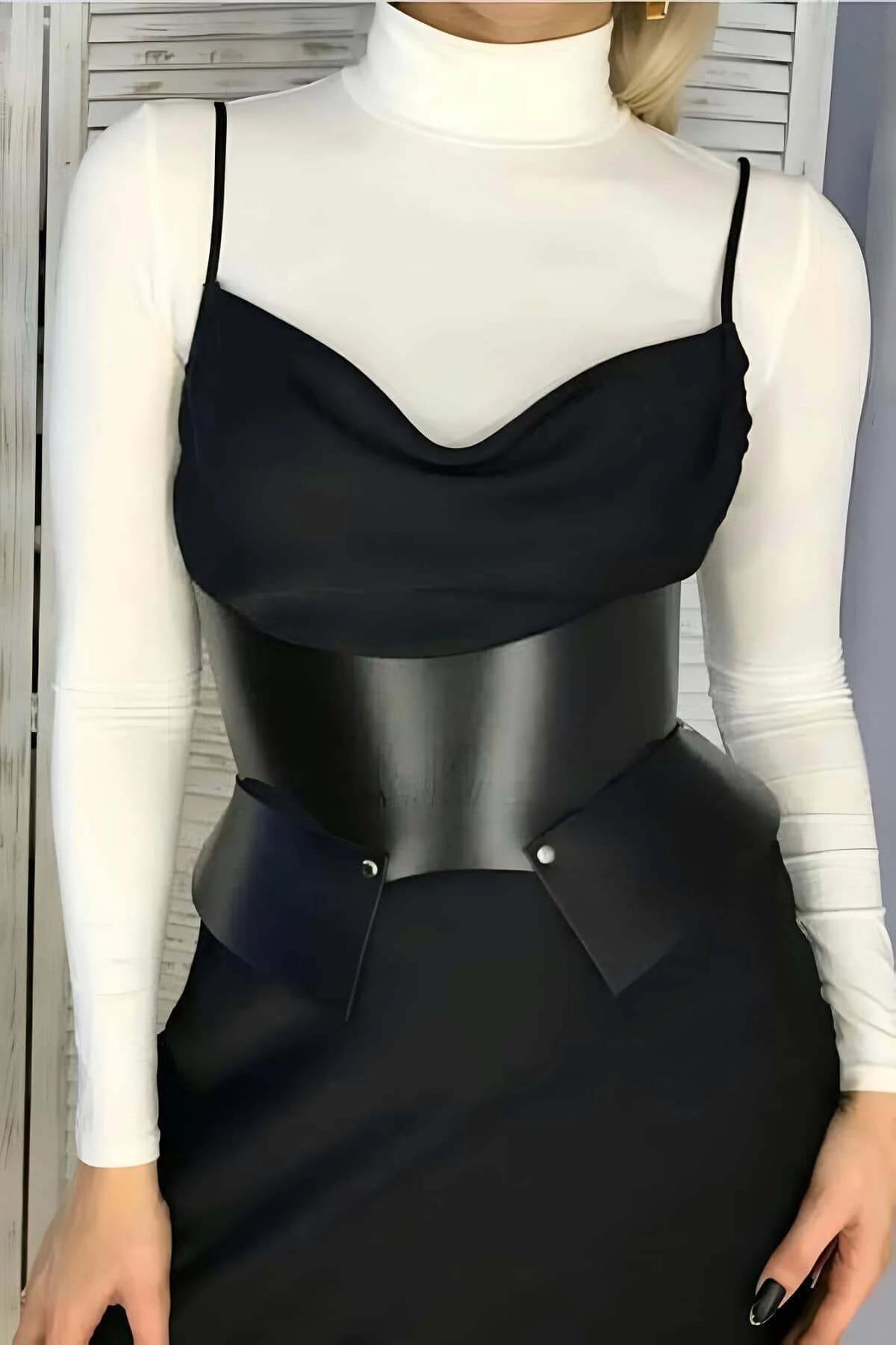 black faux leather waist cincher belt with angular tab closure and silver stud detail worn over white turtleneck