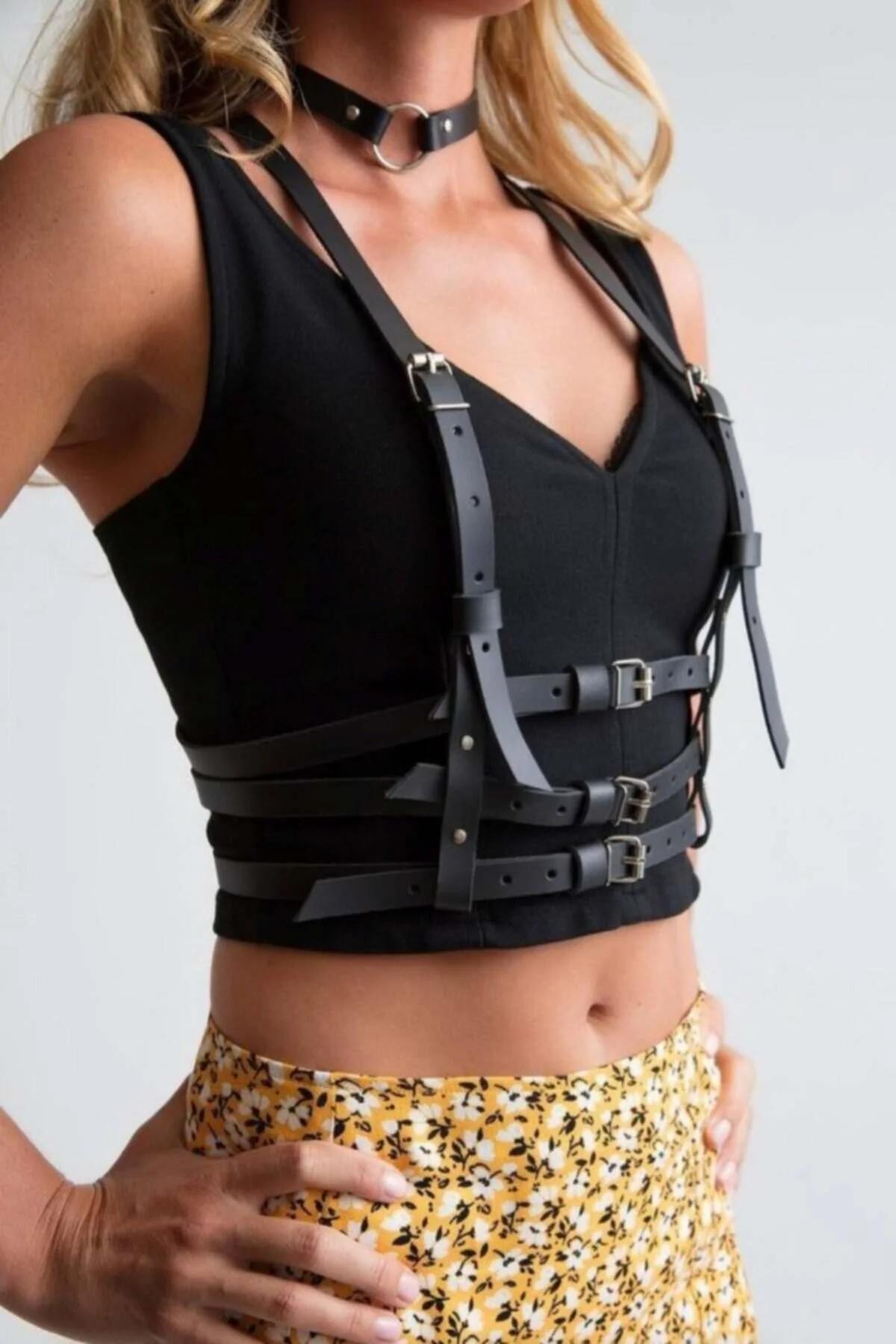 Black faux leather body harness with three silver buckles at center front and matching O-ring choker worn over black crop top