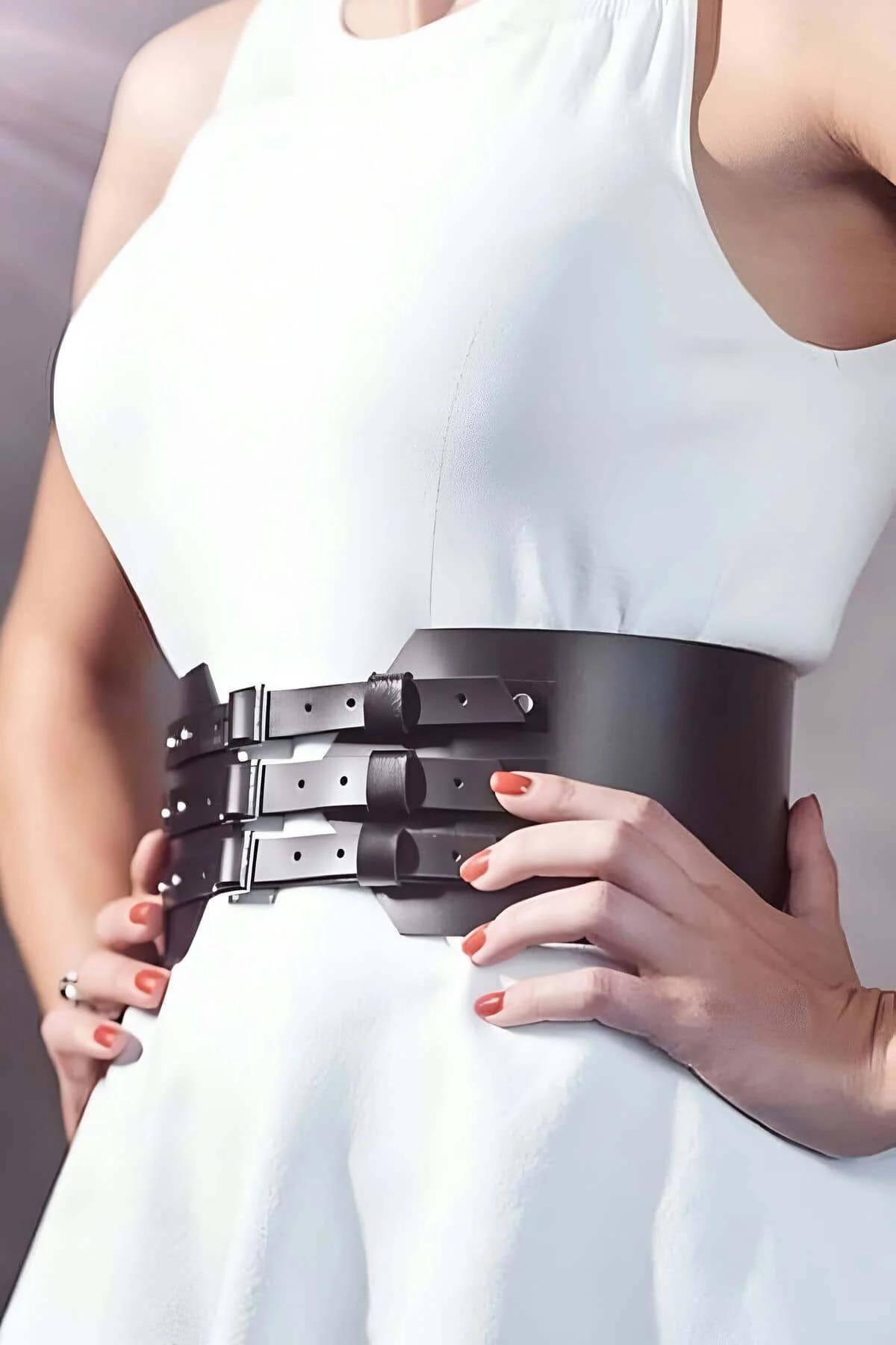Wide dark brown faux leather corset belt with three silver buckle straps worn over white dress
