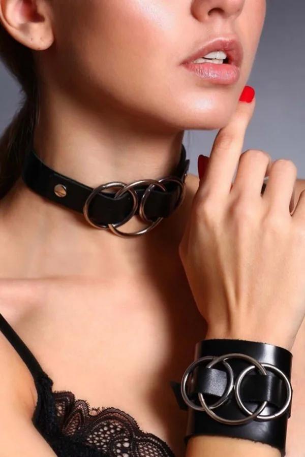Black vegan leather choker and wide wrist cuff set with three gunmetal O-rings, worn together on model