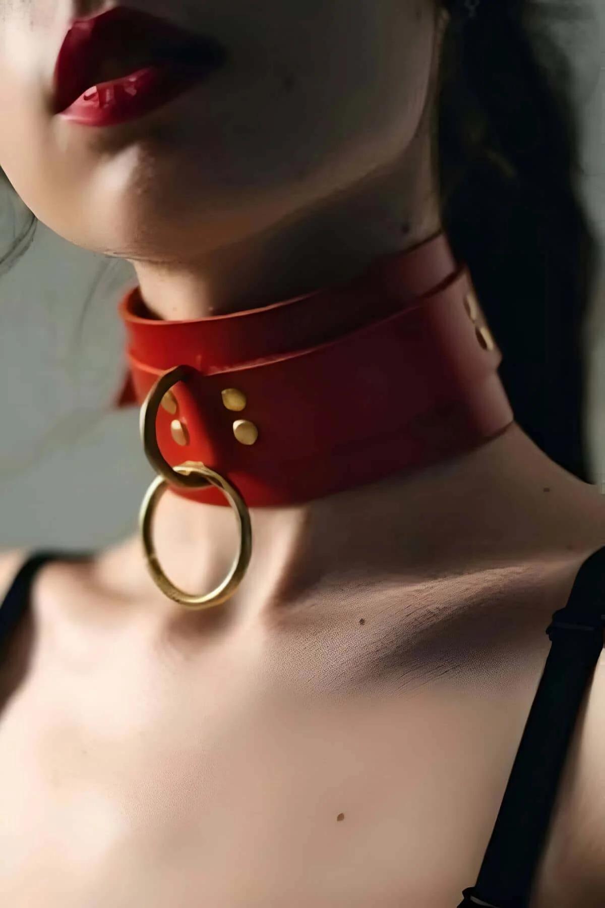 Red wide faux leather choker collar with large gold O-ring front and gold rivet studs worn on neck