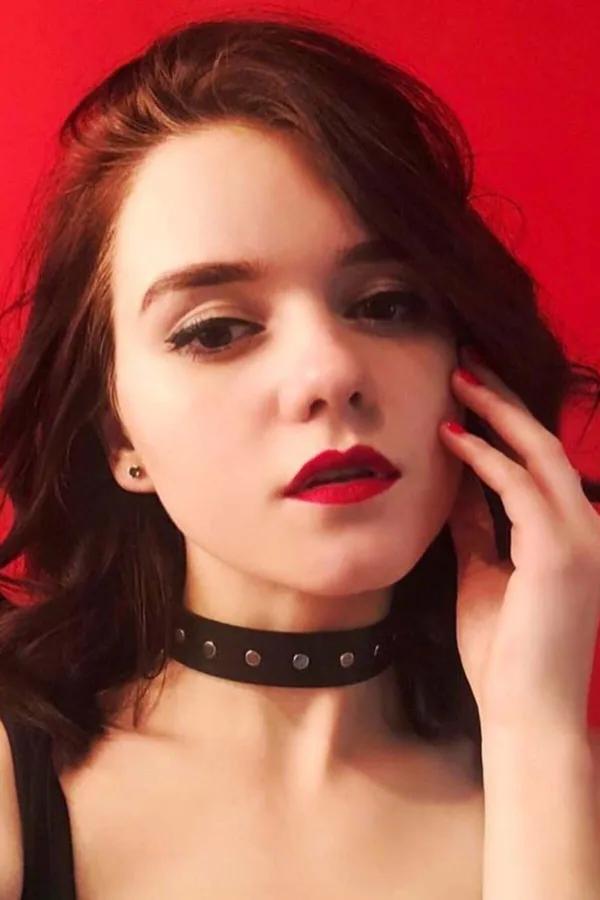 Adjustable black faux leather choker with silver dome rivets and front O-ring worn at mid-throat