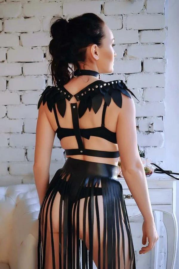 black faux leather winged shoulder harness with studded epaulettes and multi-strap back, paired with long fringe skirt, rear