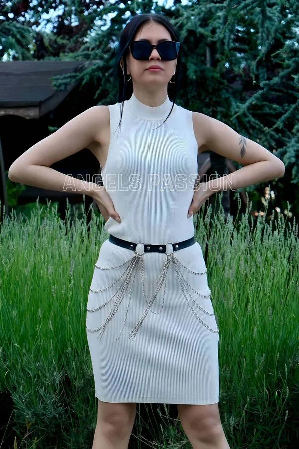 Black faux leather adjustable belt with cascading silver multi-chain draping worn over white ribbed dress