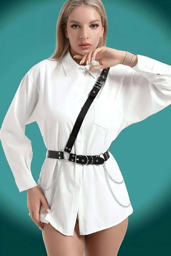Black faux leather chest harness belt with triple silver O-ring buckles and draped silver chains worn over white shirt