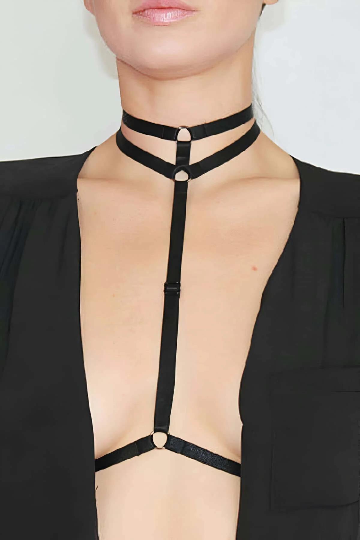 Black double strap choker body harness with gold O-ring hardware and vertical center strap worn over open black blazer