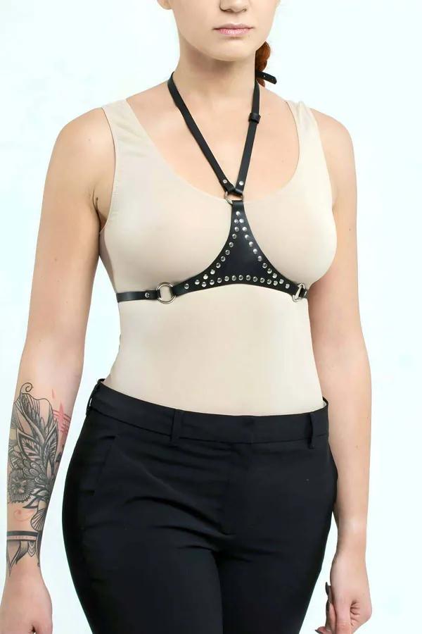 black faux leather underbust harness with silver studs and halter strap worn over beige tank top