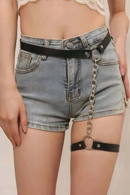 black faux leather waist garter harness with detachable silver link chain and O-ring hardware over denim shorts