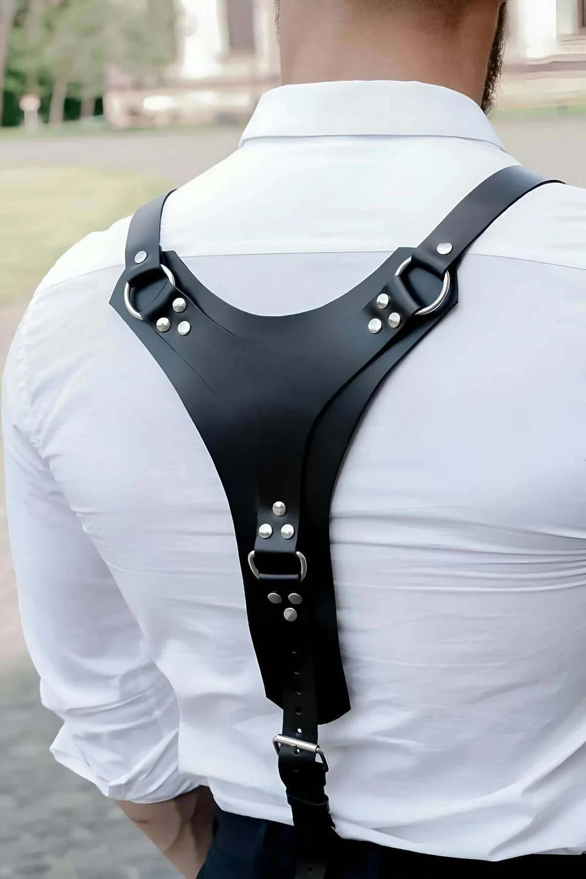 black faux leather Y-back body harness with silver O-rings and rivet studs worn over white shirt, rear view