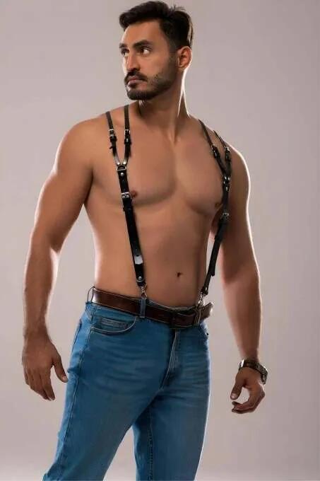 black faux leather adjustable shoulder harness with silver buckles worn over bare chest with jeans