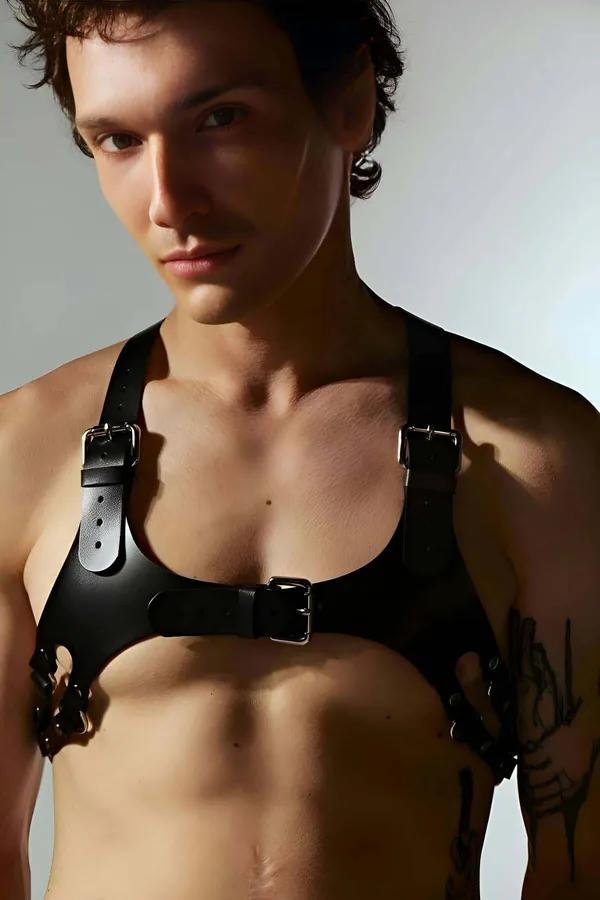 Black faux leather chest harness with silver buckles and D-rings worn by male model, matte finish