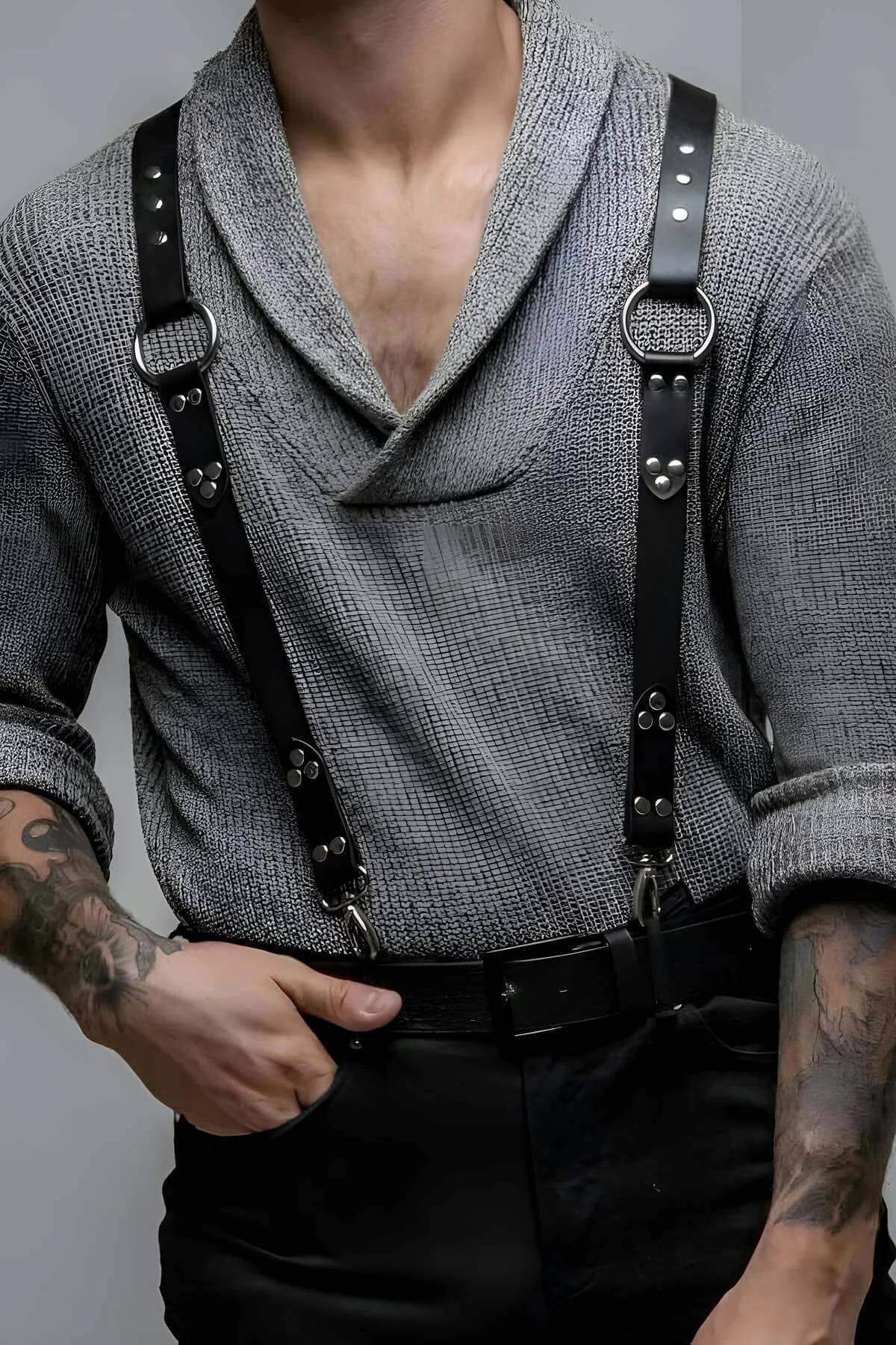 Black faux leather shoulder harness with silver O-rings and rivet studs worn over gray knit sweater