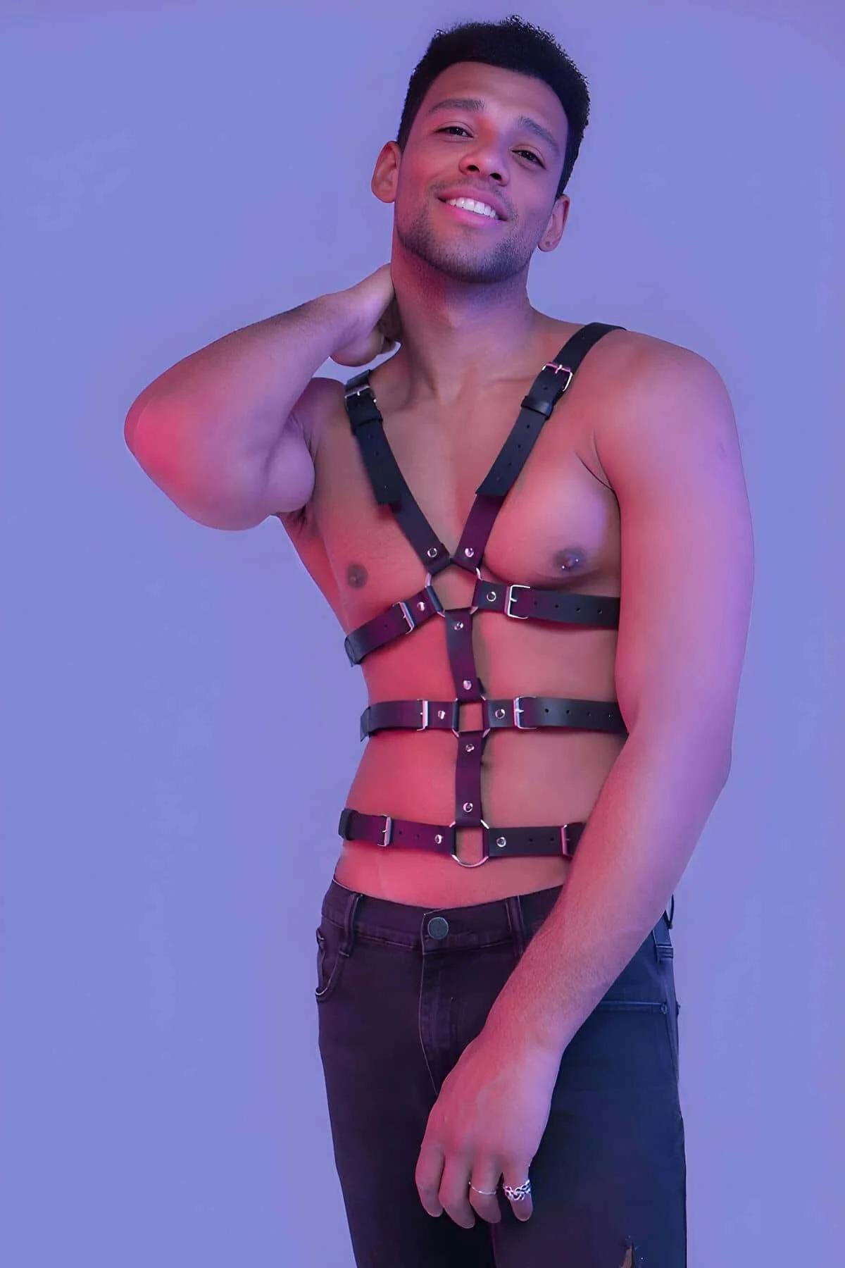 Black faux leather full body chest harness with silver O-rings and pin buckles worn by a man