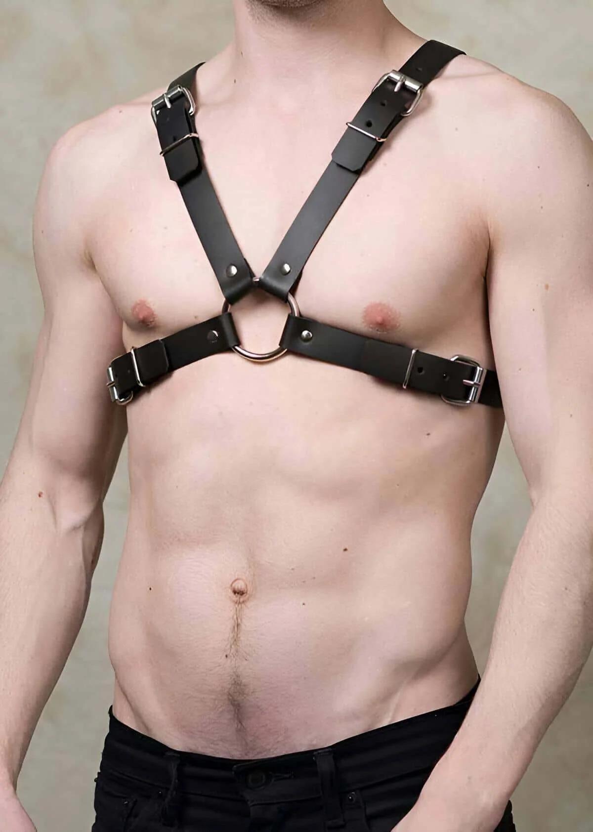 Black faux leather chest harness with silver O-ring and four pin buckles worn on male torso