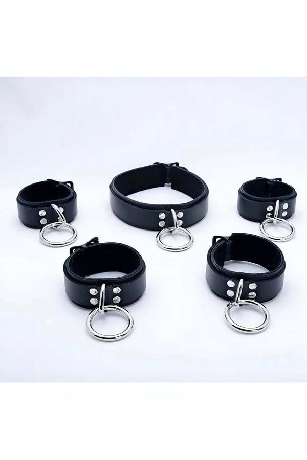 Black faux leather O-ring choker and four matching cuffs set with silver zinc alloy rings laid flat