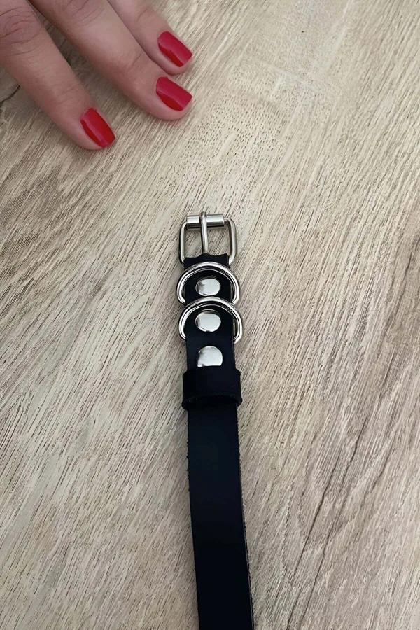 Black vegan leather strap with dual silver D-rings and pin buckle on wooden surface
